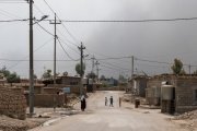 Une des rues principales du camp. Le ciel est obscurci par des fumées noires en provenance des combats autour de Mossoul.